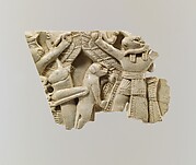 Plaque fragment with a monkey and a locust between a winged figure and ram-headed figures