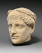 Limestone head of beardless male votary with wreath of leaves