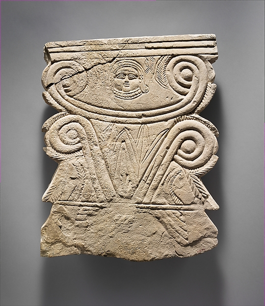 Limestone funerary stele with volutes and a Hathor head