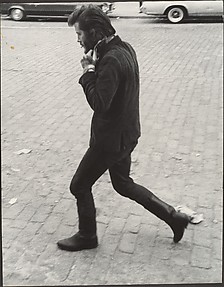[Street Scene: Man in Boots Walking and Adjusting His Collar, New York City]