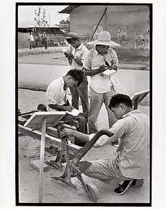 Visitors take notes on a peasant invention at National Farm Implements Exhibit, Peking