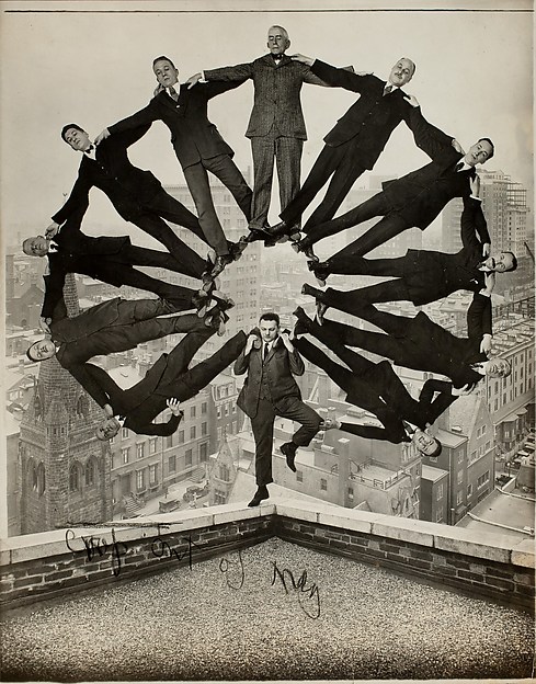 [Man on Rooftop with Eleven Men in Formation on His Shoulders]