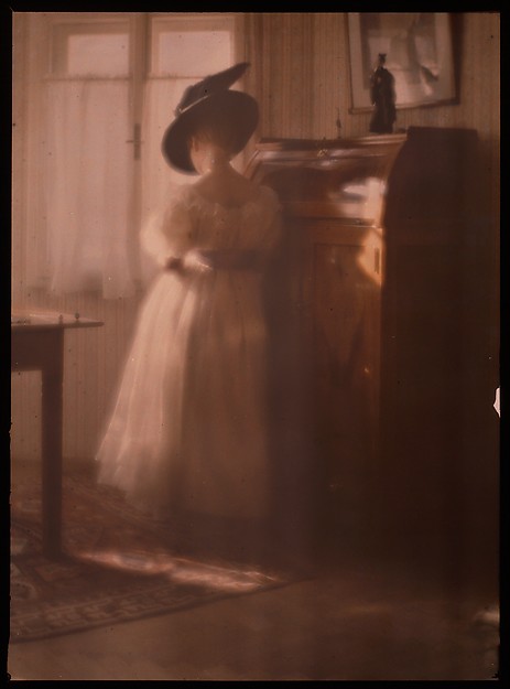 [Lady in White Dress Leaning Against Desk]