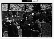 [Two Women in Conversation at Outdoor Country Auction with Graveyard in Distance]