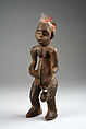 Figure: Female with Bell, Wood, feathers, brass bell, fibers, Bamileke (Bagam)