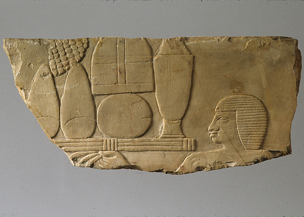 Raised relief fragment with head of an offering bearer and offerings