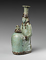 Faience double-spouted vessel in the form of a kneeling woman holding a jar, Faience, East Greek