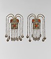 Boy's Amulet, One of a Pair, Silver; fire-gilded with gallery wire, stamped bead and applique decoration, rams' heads upper terminations, link chains, bells, embossed pendants and table cut carnelians