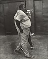 [Man Wearing Short-Sleeved Plaid Shirt and Woman in Sandals Walking on Street, New York], Leon Levinstein  American, Gelatin silver print