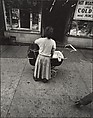 [Young Girl in White Sweater Holding Baby Stroller, New York], Leon Levinstein  American, Gelatin silver print