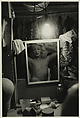 Blonde female impersonator framed in a mirror beneath a light bulb, N.Y.C., Diane Arbus American, Gelatin silver print