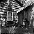 [Woman Leaning Against House Façade, Boy Seated, and Girl Leaning Against Shed], Ralph Eugene Meatyard  American, Gelatin silver print
