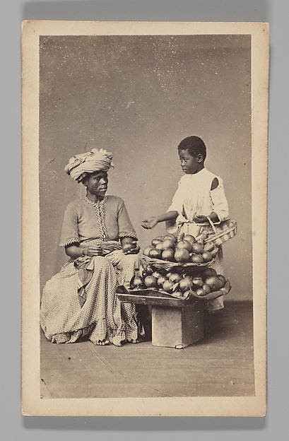 [Studio Portrait: Seated Woman and Standing Boy Street Vendors with Vegetable Baskets, Brazil]