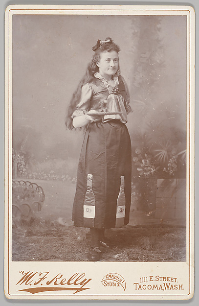 [Merchants' Carnival Portrait: with Wine Bottle Applique on Skirt, Tacoma, Washington] by M. F. Kelly, The Metropolitan Museum of Art
