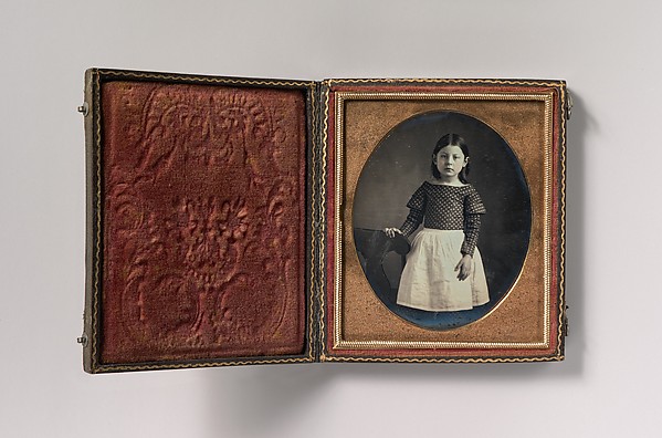 [Young Girl Wearing Waist Apron, Resting Hand on Chair]