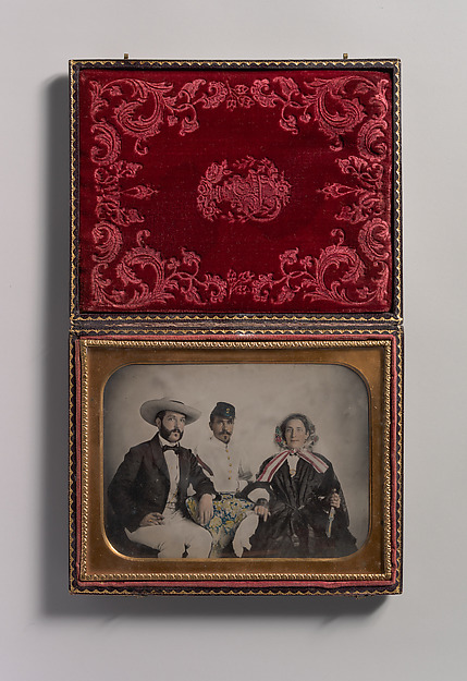 [Two Men, One in Military Garb, and a Woman, Seated Around a Table]
