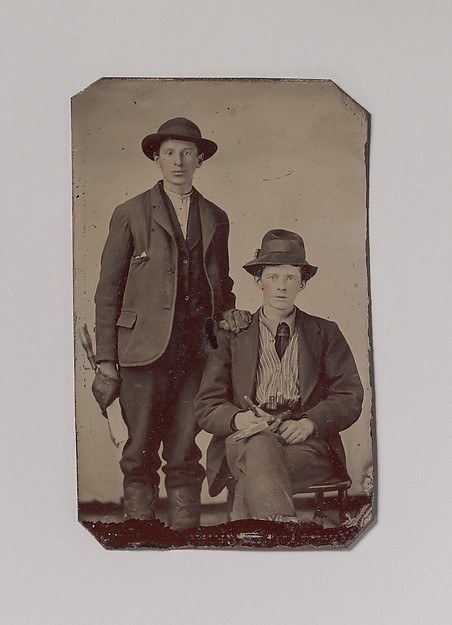 [Two Young Men, One Seated and One Standing, Holding Carpentry Tools]