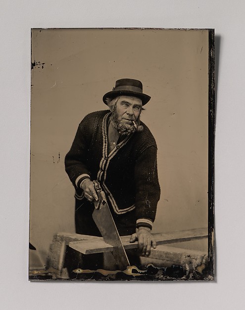 [Carpenter Sawing a Plank of Wood]