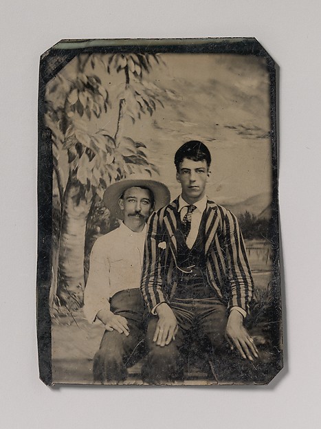 [Young Man in a Striped Jacket, Sitting on the Lap of Another Man in Front of Painted Outdoor Backdrop]