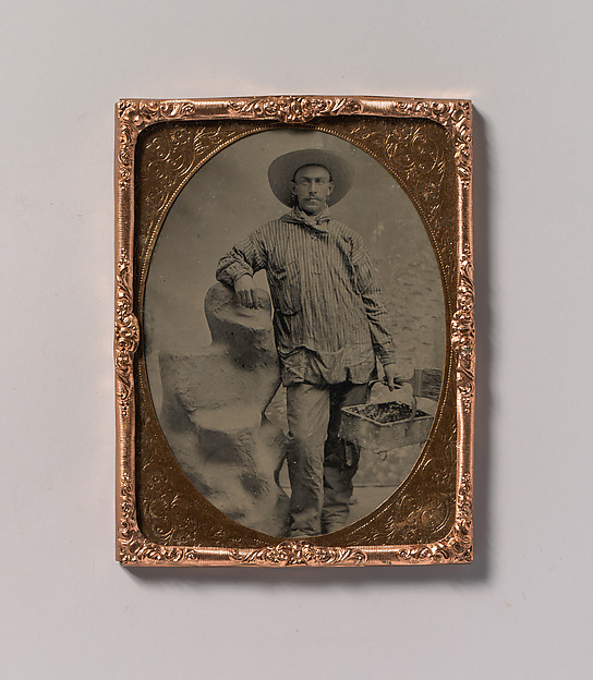 [Workman Holding Brush and Rectangular Tray, Arm Resting on Fake Rock]