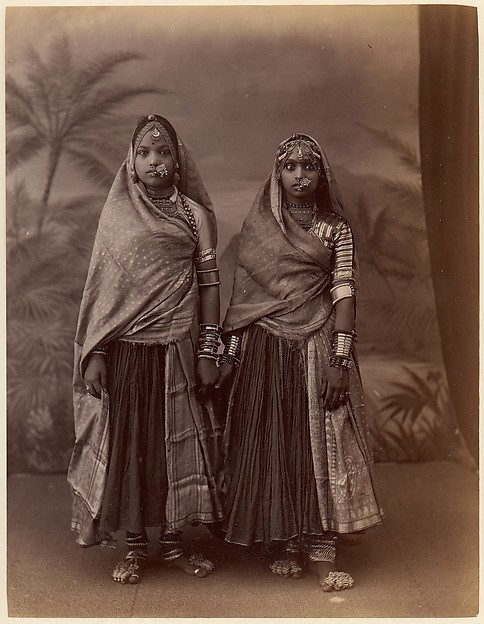 [Two Hindu Women in Elaborate Jewelry, Before Studio Backdrop with Palm Trees]